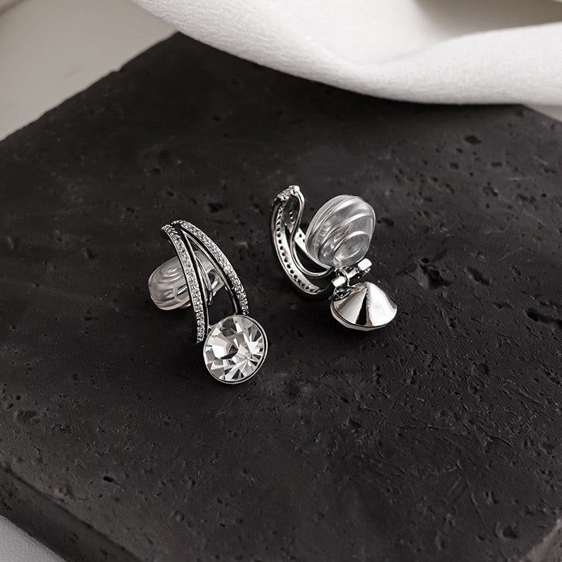 Model wearing silver diamond drop clip-on earrings, demonstrating the sparkling round crystal solitaire dangling on an unpierced ear.