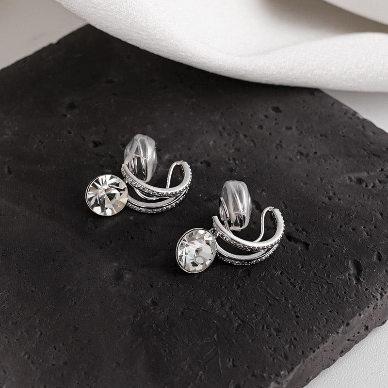 Side profile of a model styling the silver diamond drop clip-on earring paired with a silver ear cuff for a layered ear stack effect
