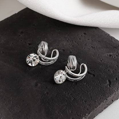 Side profile of a model styling the silver diamond drop clip-on earring paired with a silver ear cuff for a layered ear stack effect