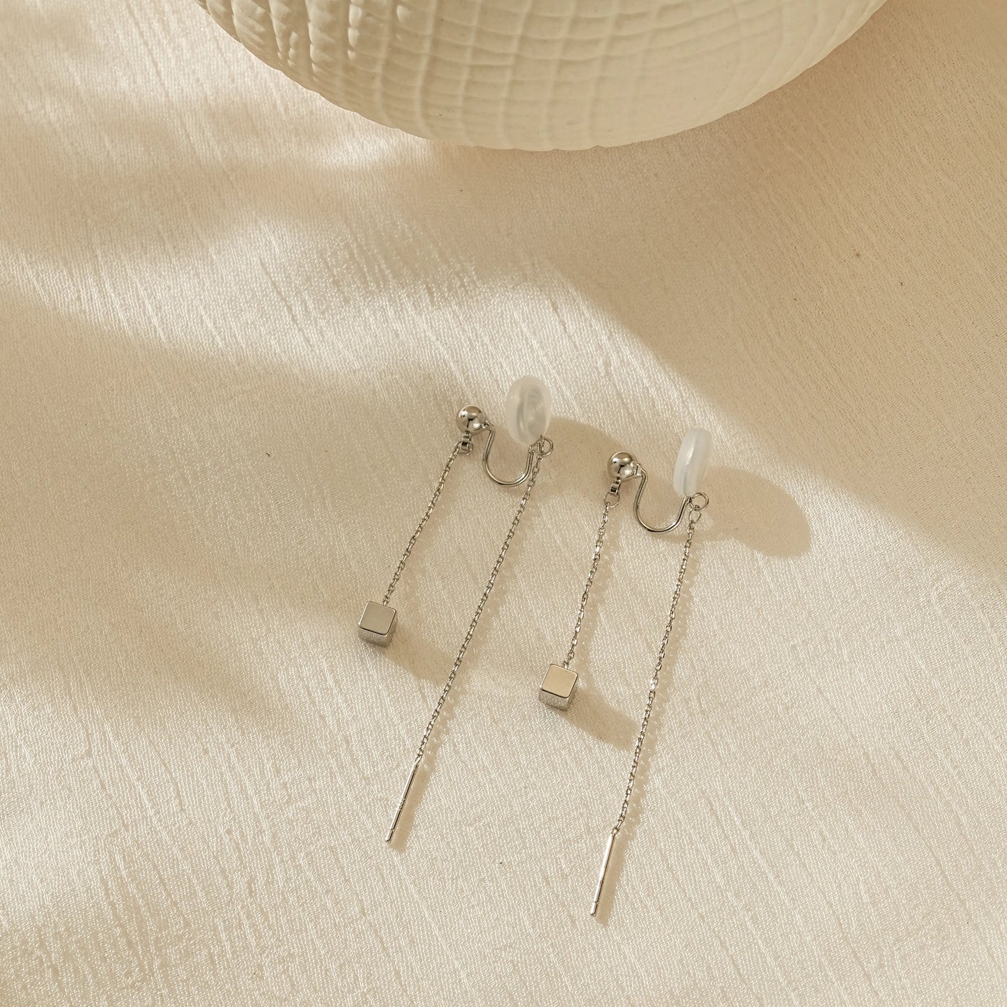 Polished silver linear threader clip-on earrings, minimalist long chain design.