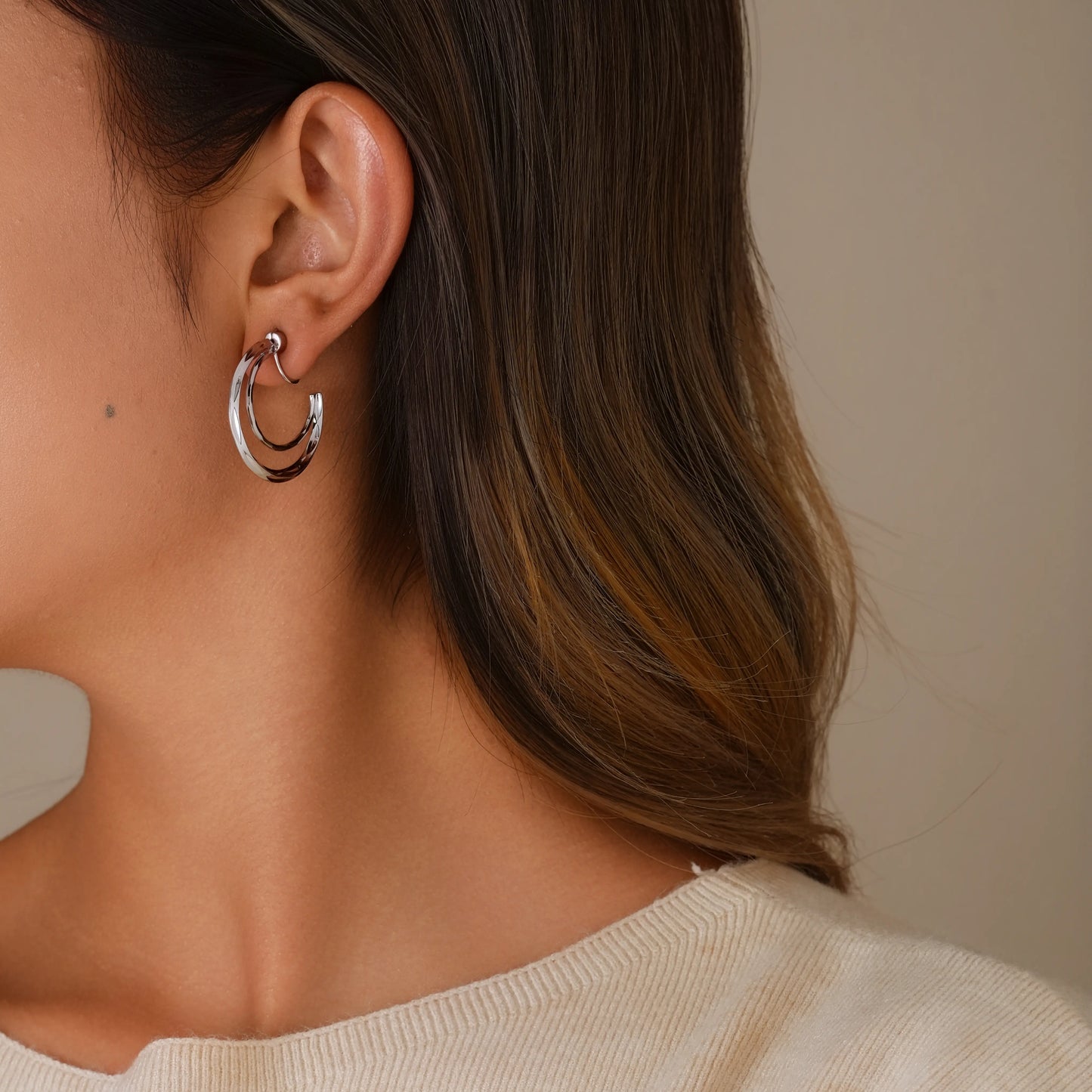 Model styling silver crescent double hoops for a modern, minimalist ear stack look.