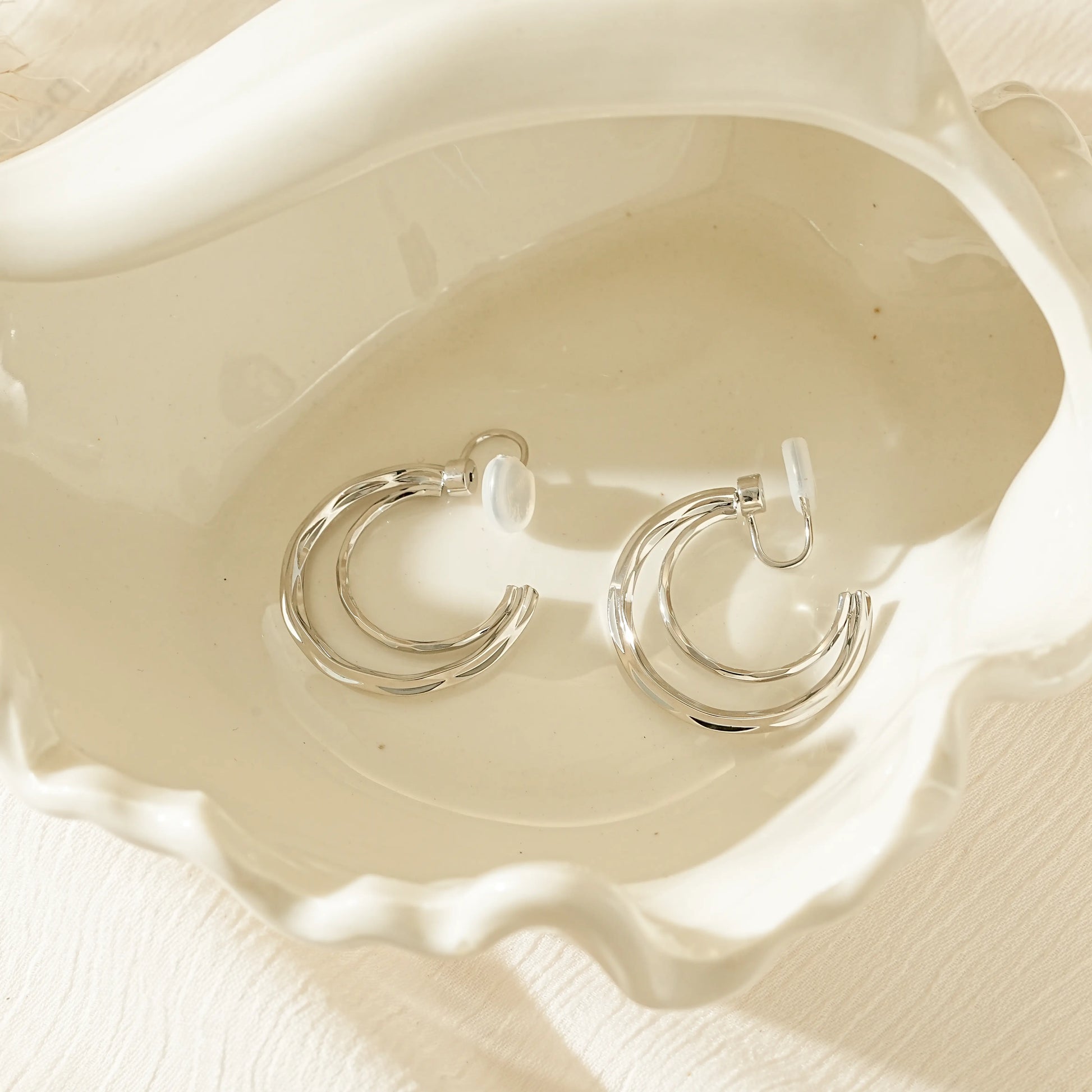 Close-up of the architectural silver double hoop silhouette for non-pierced ears.