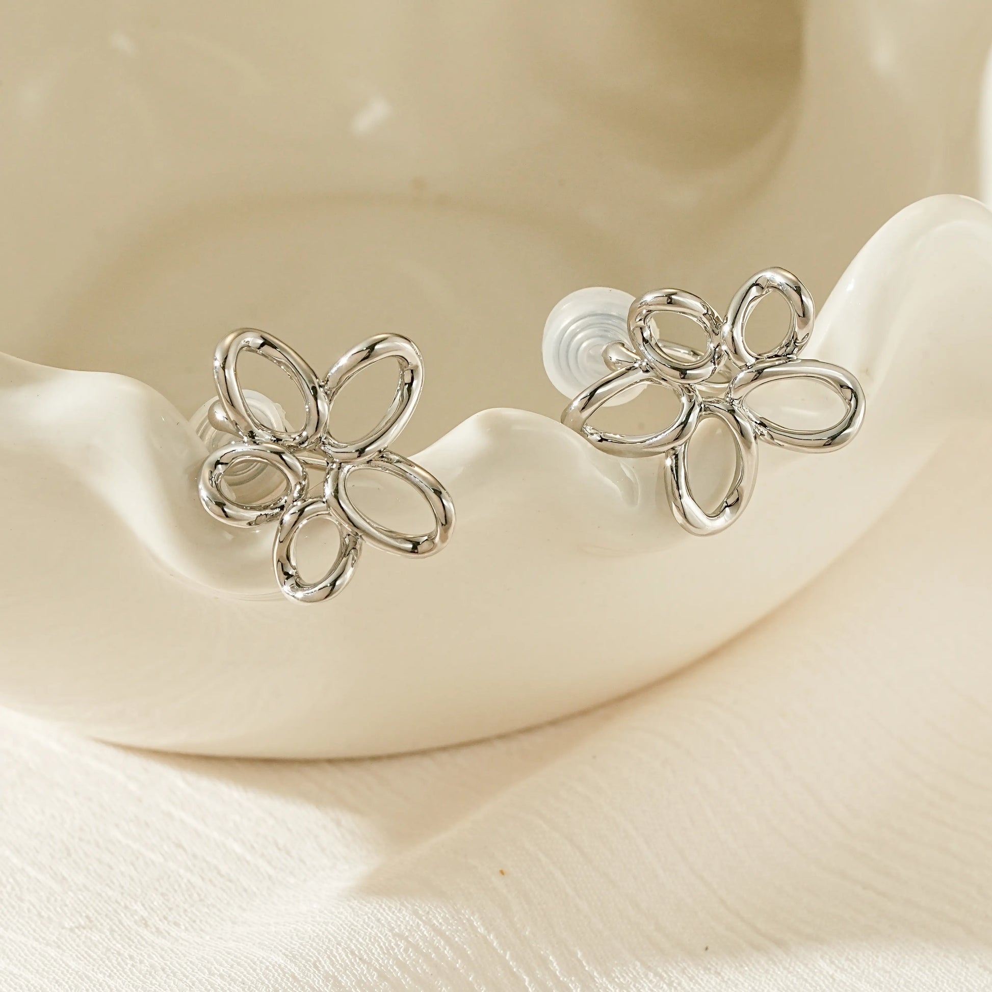 Close-up of the architectural silver wire floral silhouette on non-pierced earrings.