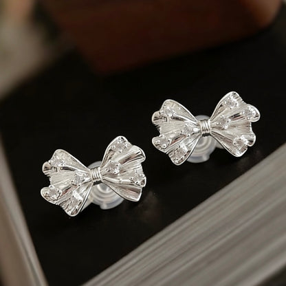 Side profile of a model styling the silver bow clip-on studs as a base piece, paired with a sleek silver ear cuff for a curated, no-piercing ear stack