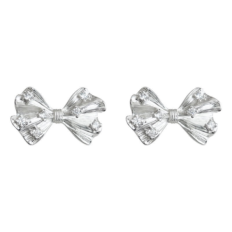 Detailed macro shot showing the back of the silver bow earring, highlighting the gentle clip mechanism and soft clear silicone comfort pad