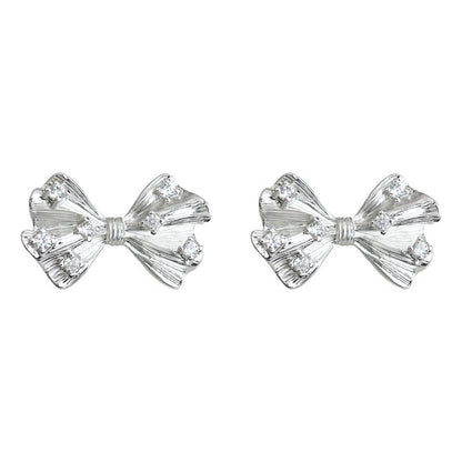 Detailed macro shot showing the back of the silver bow earring, highlighting the gentle clip mechanism and soft clear silicone comfort pad