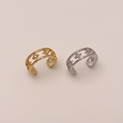 A gold double-band ear cuff featuring small star shapes set with clear cubic zirconia crystals, resting against a neutral background.