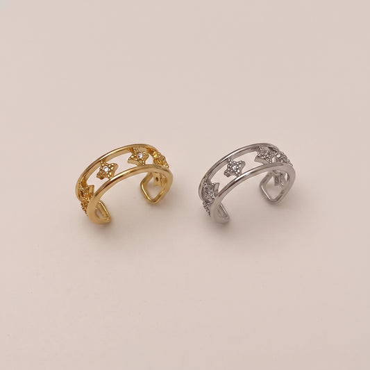 A gold double-band ear cuff featuring small star shapes set with clear cubic zirconia crystals, resting against a neutral background.
