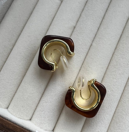 Angled close-up of a gold statement hoop earring showing the depth of the amber stone and the thickness of the gold plating. The light reflects off the polished metal surface, highlighting the high-quality vintage retro design.