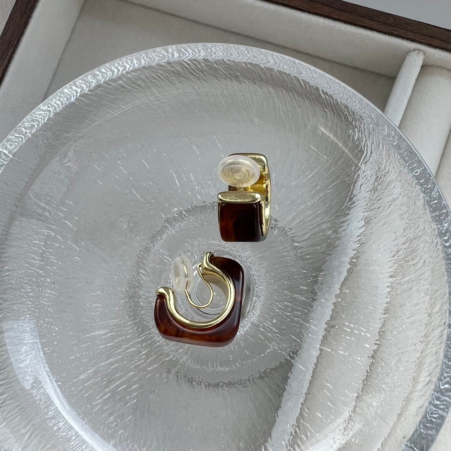 Back view of chunky gold amber hoop earrings, revealing the invisible clear resin clip-on mechanism. The image shows the flexibility of the resin clip, designed for non-pierced ears without the use of painful metal hinges.