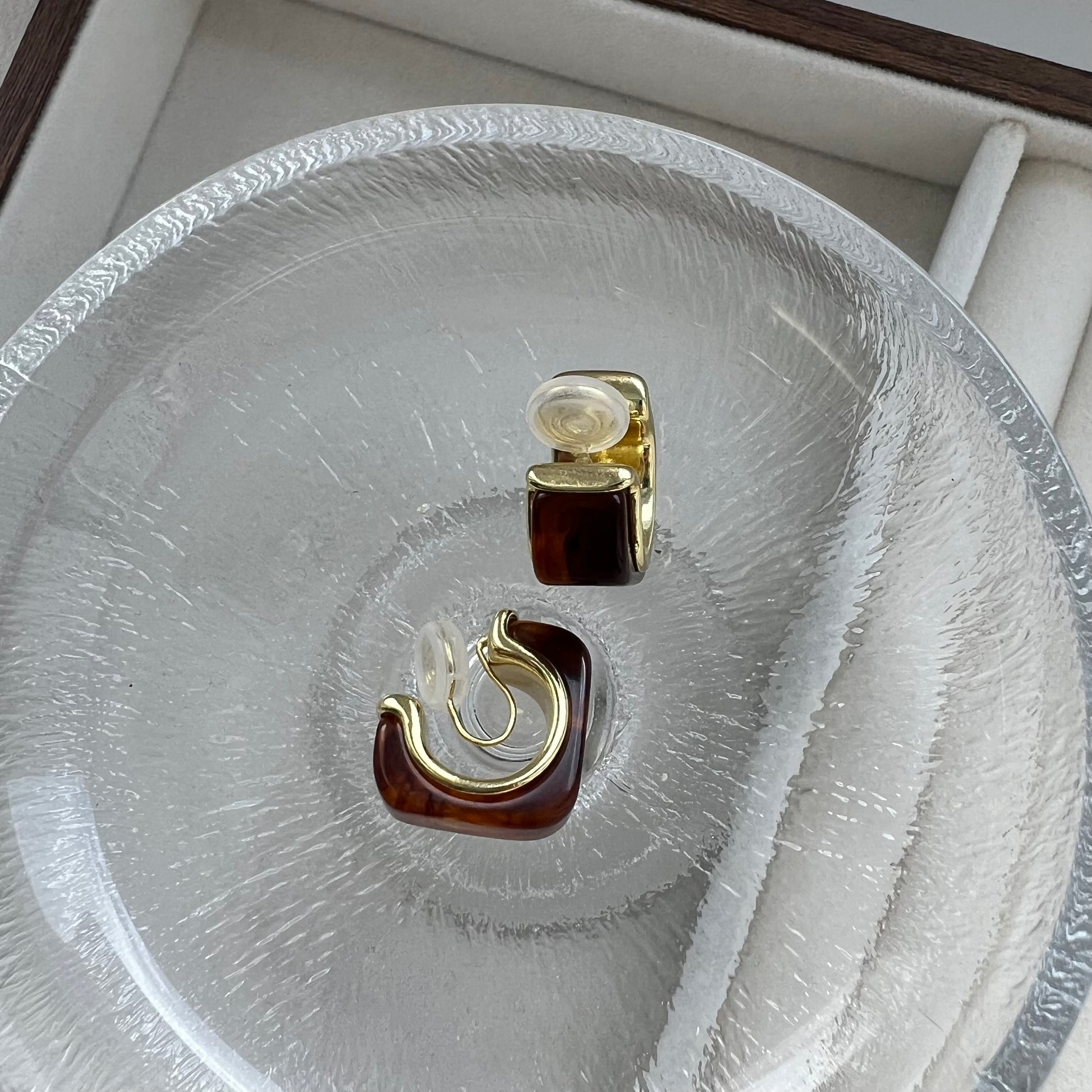 Back view of chunky gold amber hoop earrings, revealing the invisible clear resin clip-on mechanism. The image shows the flexibility of the resin clip, designed for non-pierced ears without the use of painful metal hinges.
