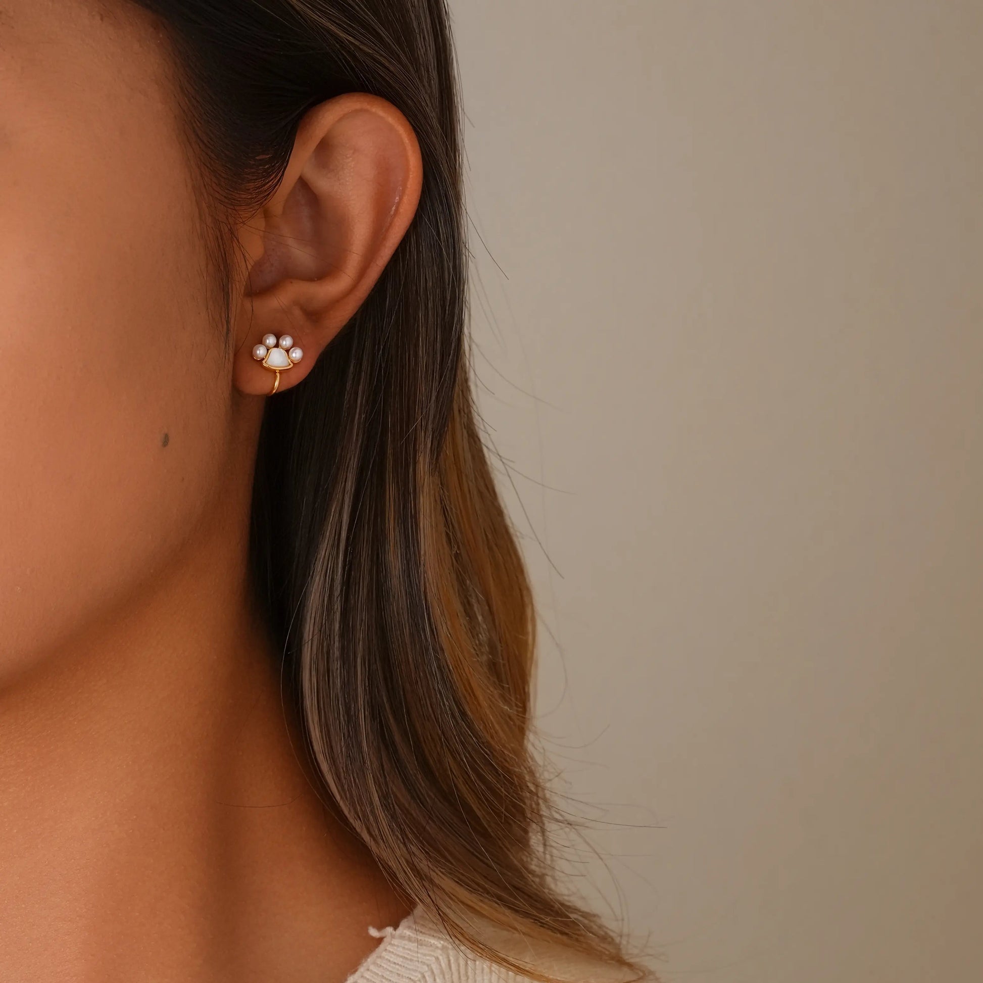 Model wearing the tiny paw print pearl gold earrings for a cute, everyday look.