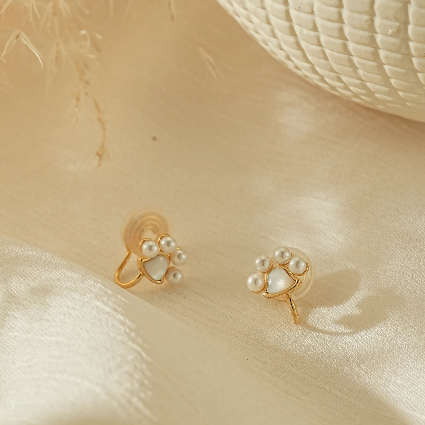 Tiny paw print pearl clip-on earrings in 18k gold plating, front view.
