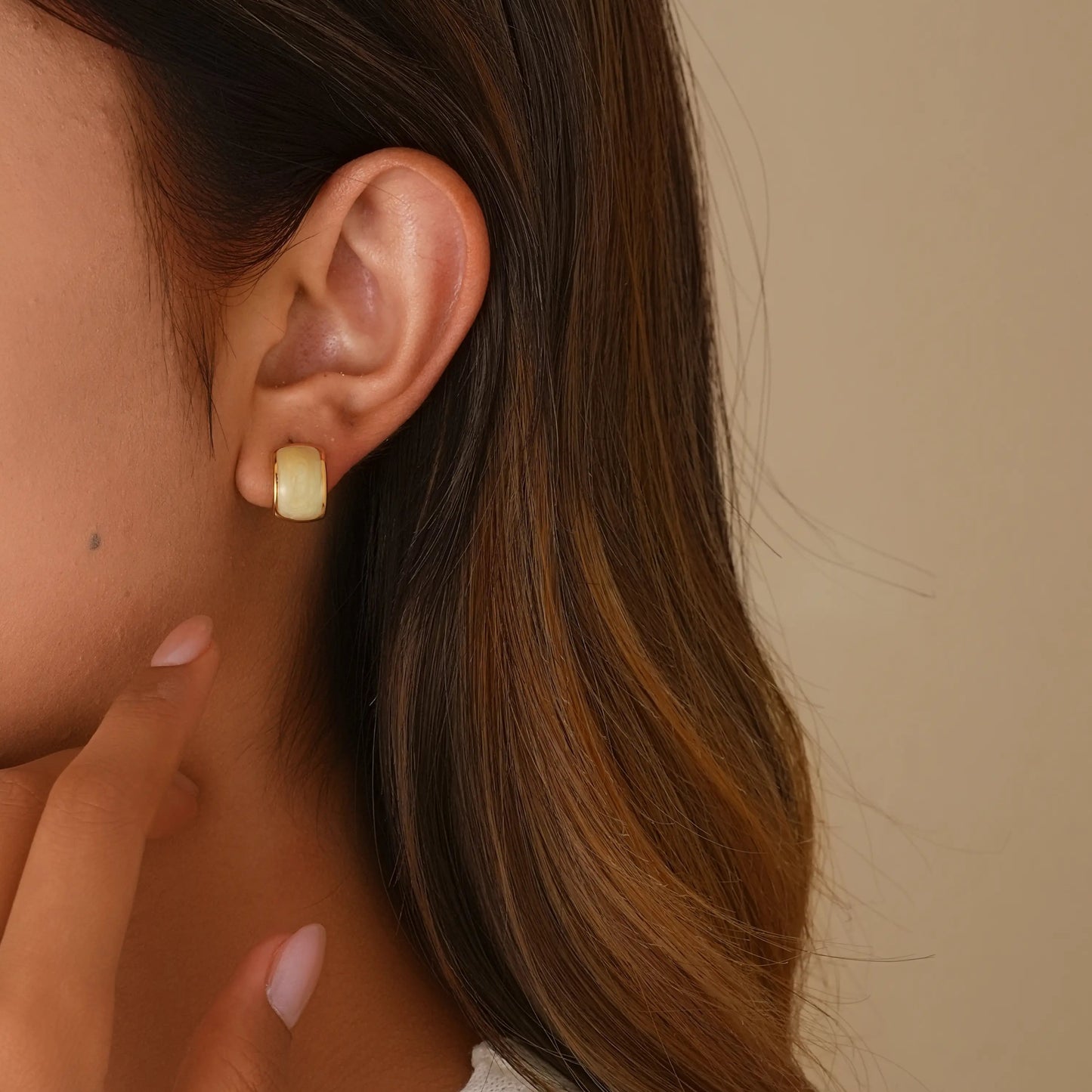 Close-up of model styling the handmade enamel earrings, showing the secure and stylish fit.