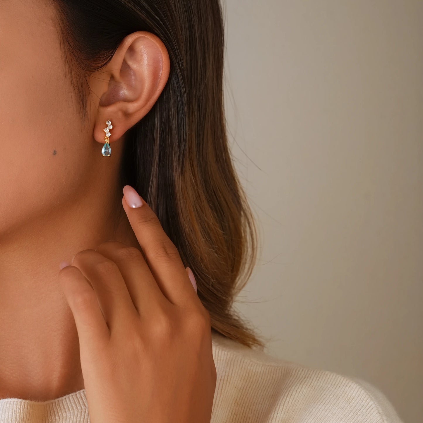 Lifestyle photo of a model styling blue gemstone clip-on earrings, showing the seamless look of a traditional piercing.