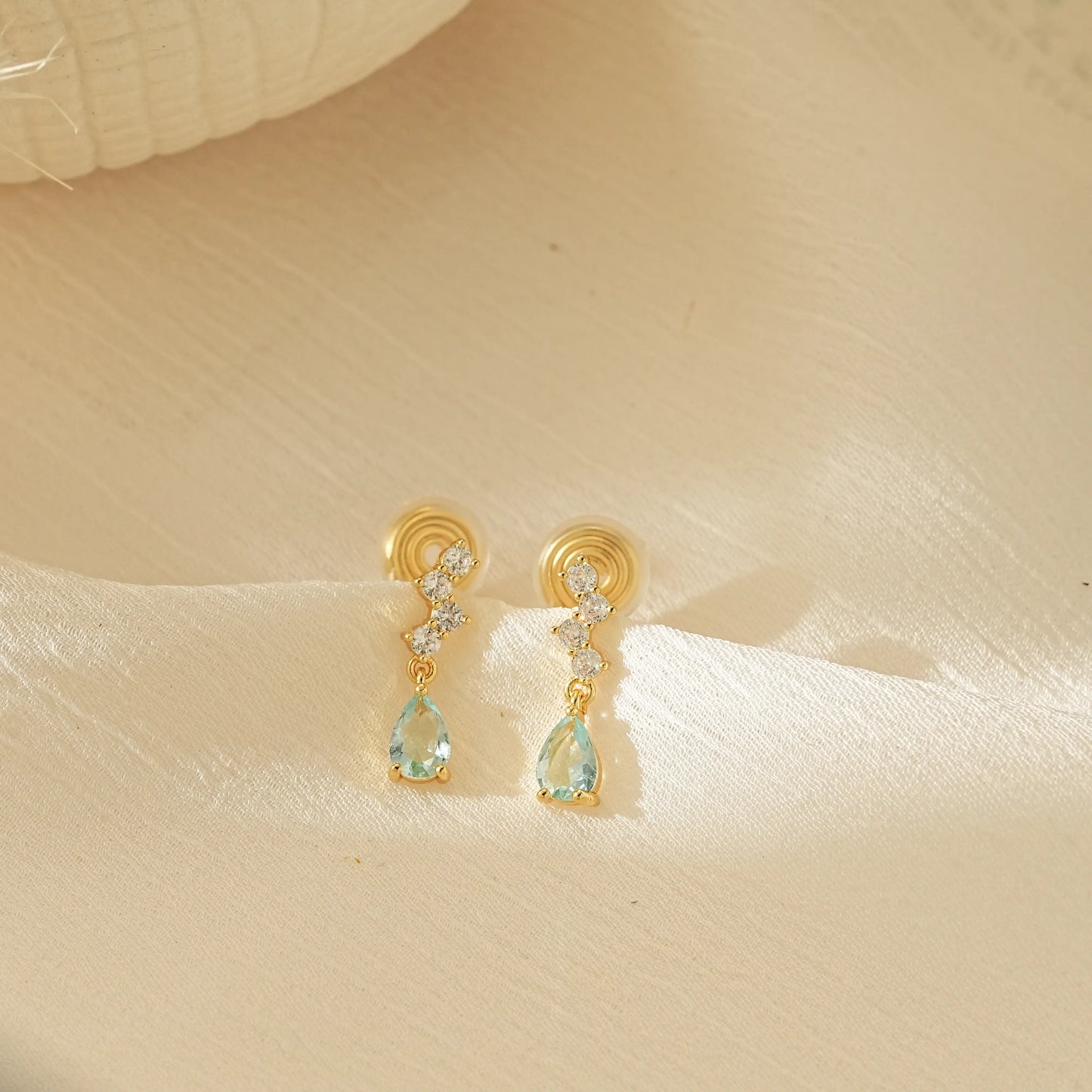 Pair of Aquamarine blue dangle drop clip-on earrings with gold settings, an elegant choice for non-pierced jewelry.