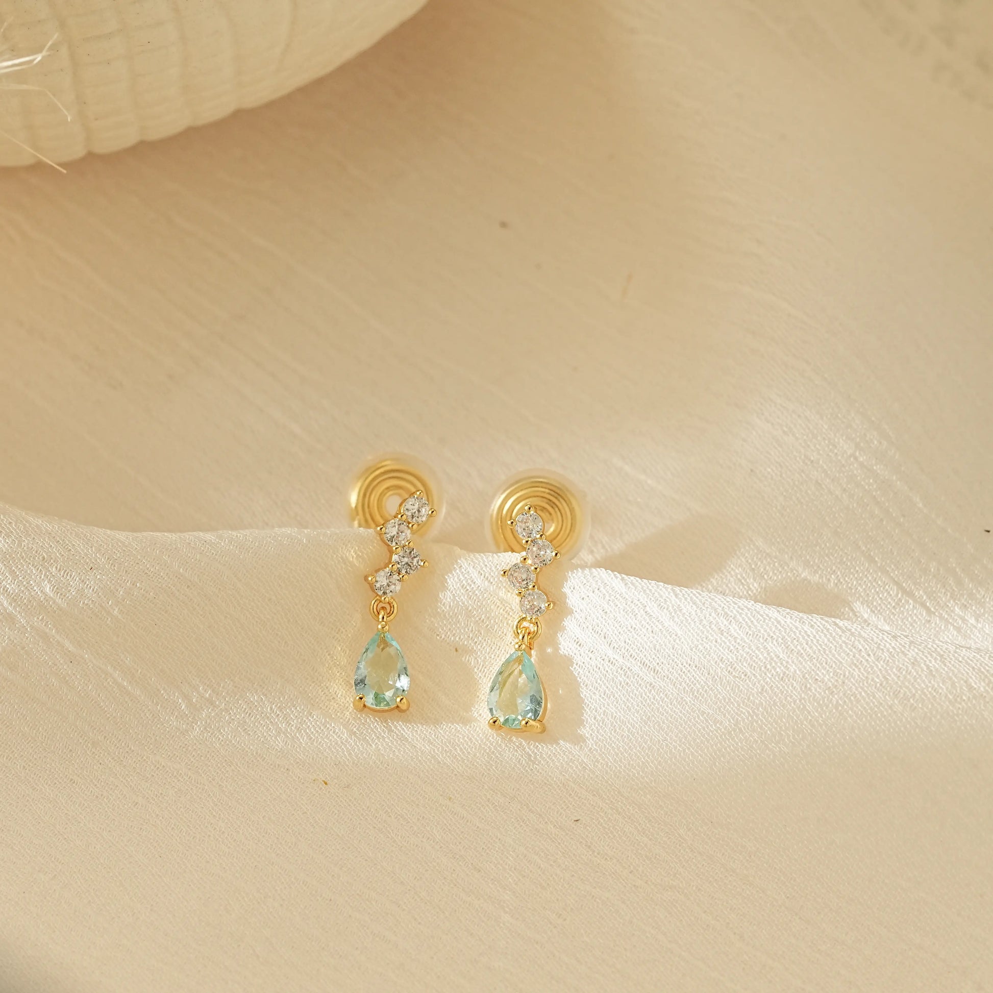 Pair of Aquamarine blue dangle drop clip-on earrings with gold settings, an elegant choice for non-pierced jewelry.
