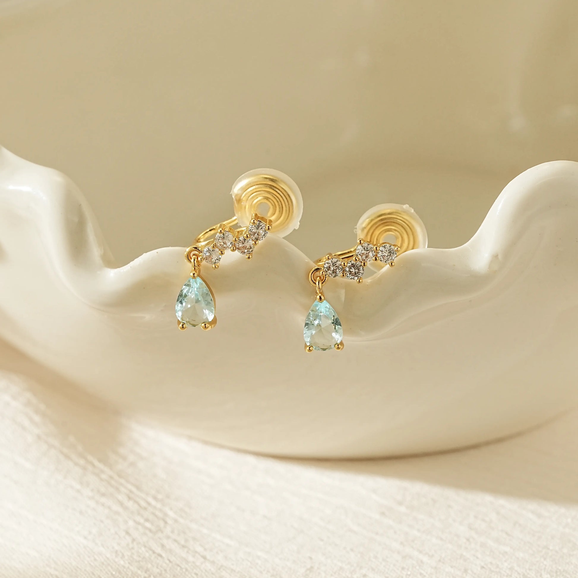 Light blue crystal clip-on earrings with a minimalist gold design, perfect for everyday style or special occasion gifts.