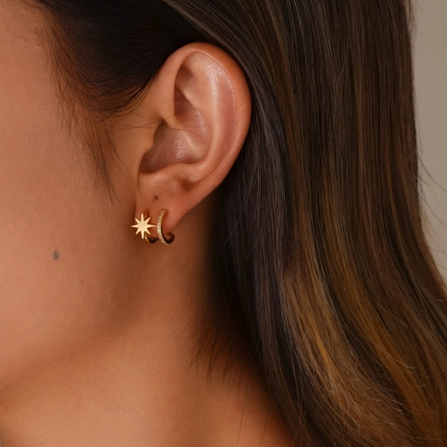 Close up of model styling 18k gold double hoop star clip-on earrings for an ear party.