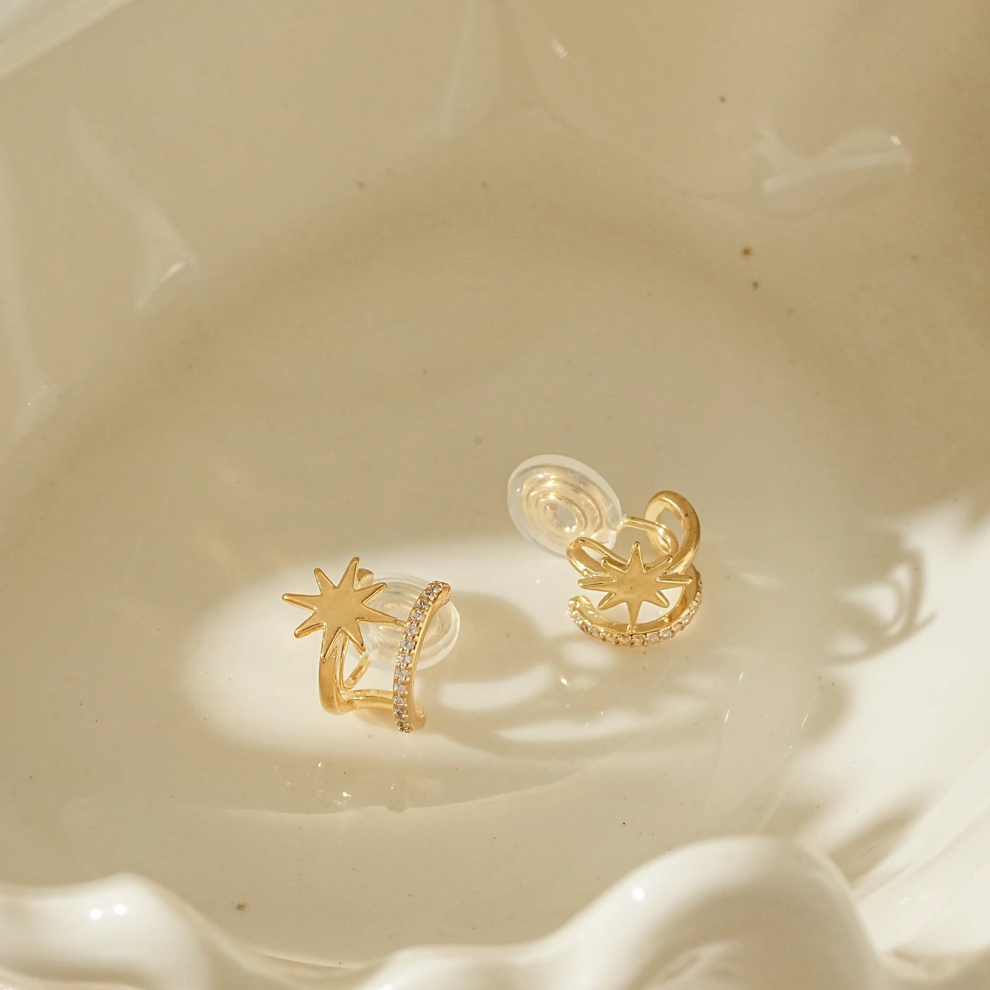 Close-up of adjustable gold star clip-on hoops for unpierced ears.