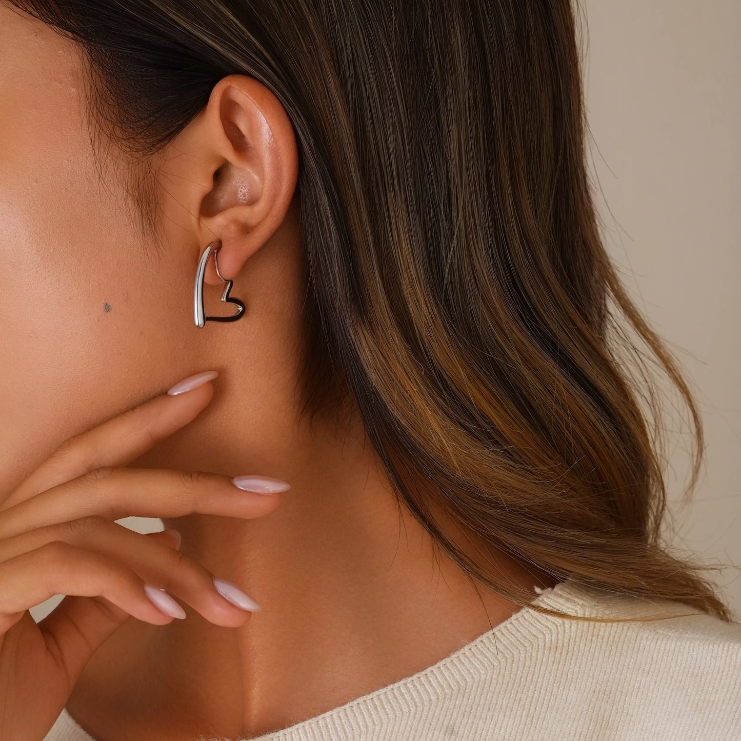 Model wearing silver chunky heart hoop clip-on earrings, showing a trendy "cool girl" look.