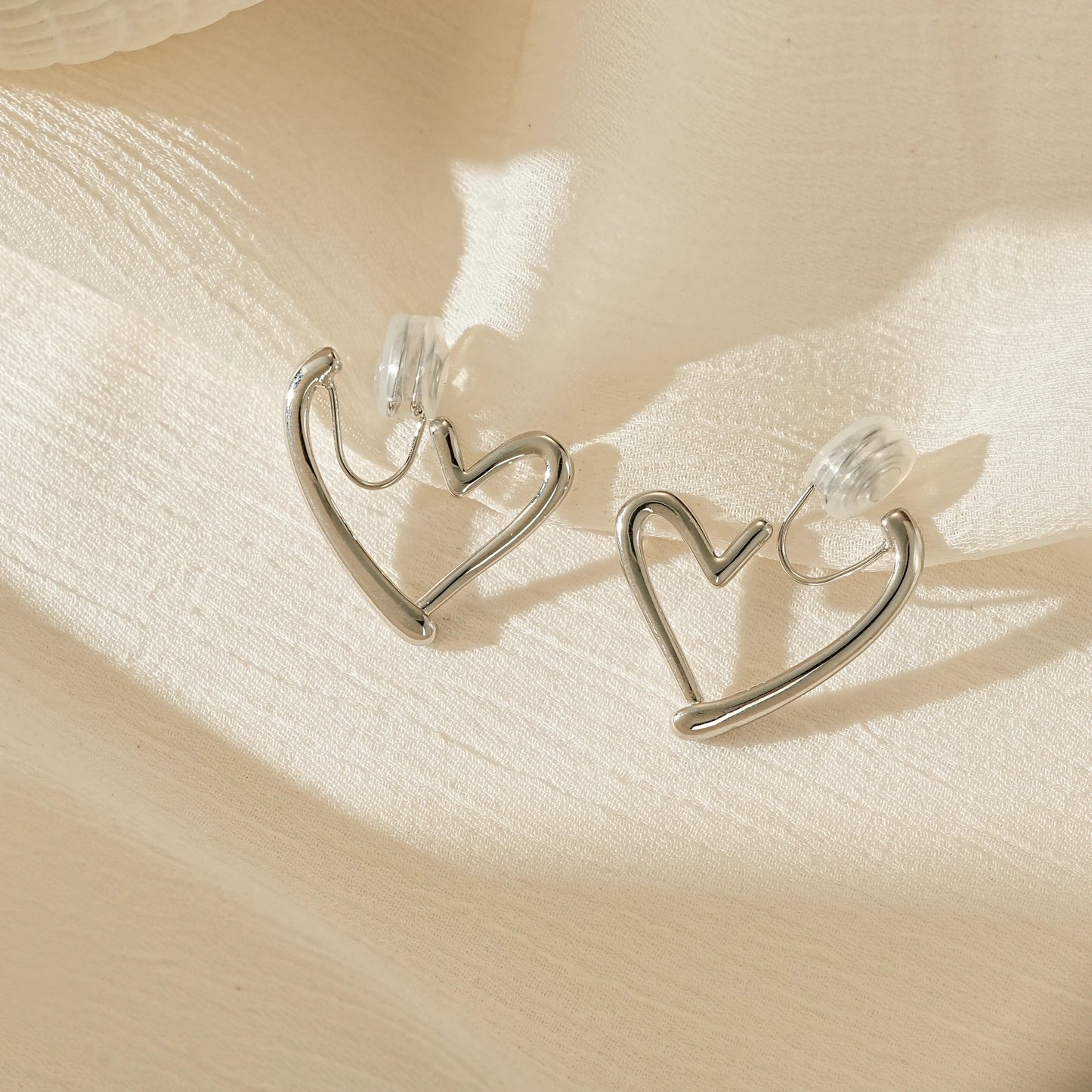 Polished silver chunky heart hoop clip-on earrings, front view showing the bold shape for unpierced ears.