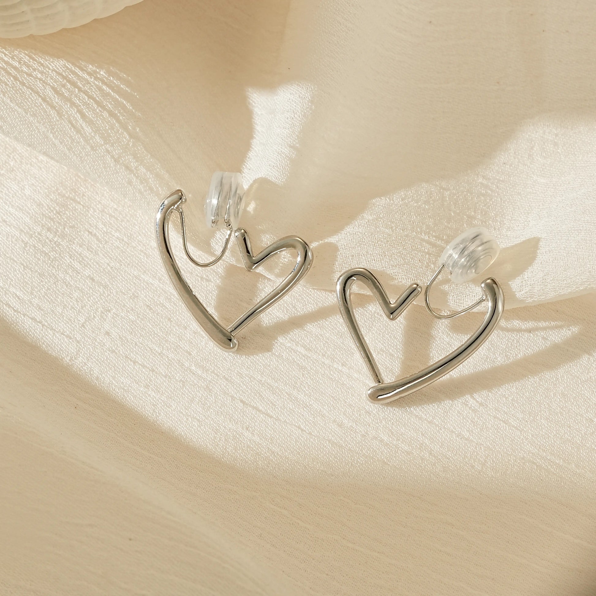 Polished silver chunky heart hoop clip-on earrings, front view showing the bold shape for unpierced ears.